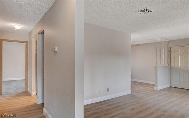 Corridor with a textured ceiling, wood finished floors, and baseboards | Image 10