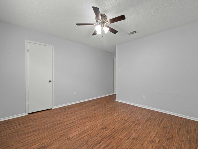 Unfurnished room with wood finished floors, a ceiling fan, and a textured ceiling | Image 11