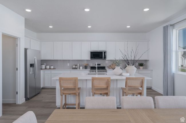 Kitchen with stainless steel appliances, a center island with sink, white cabinets, recessed lighting, and light countertops | Image 18
