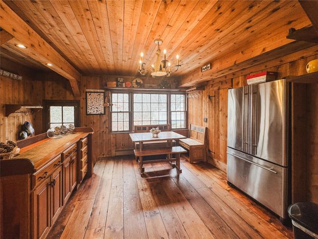 Kitchen featuring an inviting chandelier, freestanding refrigerator, wooden walls, wooden ceiling, and hardwood / wood-style floors | Image 11