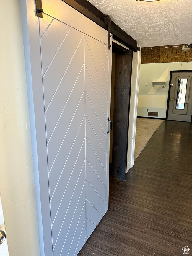 Hall with a textured ceiling, a barn door, and dark wood-type flooring | Image 13