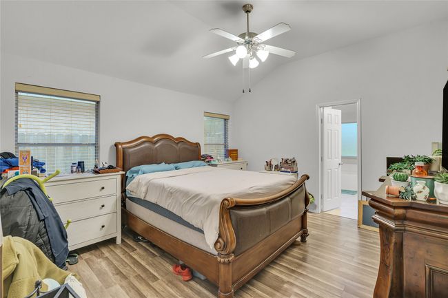 Bedroom with lofted ceiling, light wood finished floors, multiple windows, and ceiling fan | Image 17