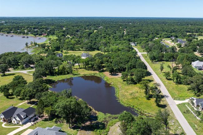Aerial view of property's location featuring a nearby body of water and a heavily wooded area | Image 7