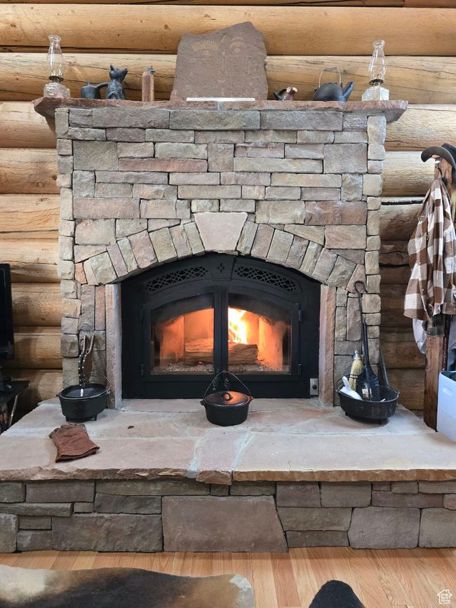 Details featuring log walls, wood finished floors, and a fireplace | Image 66