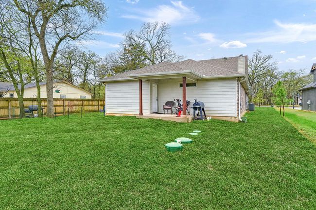 Back of property featuring fence, a chimney, a shingled roof, a yard, and a patio area | Image 28