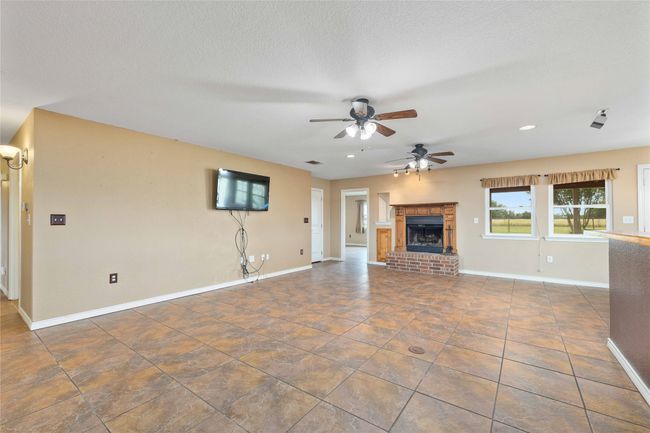 Unfurnished living room featuring ceiling fan, a fireplace, recessed lighting, and a textured ceiling | Image 7