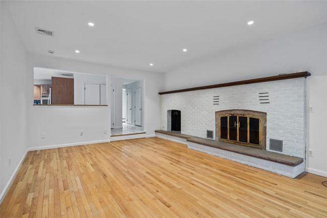 Unfurnished living room featuring a brick fireplace, wood-type flooring, and recessed lighting | Image 5