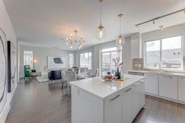 Kitchen featuring a kitchen island, backsplash, white cabinetry, and light countertops | Image 10