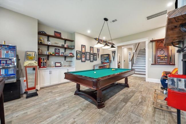 Located downstairs, the game room boasts custom tile flooring with a variation of sizes, creating a unique and dynamic design that adds character to the space. The room is perfect for entertaining, offering a relaxed atmosphere with plenty of room for a pool table and other activities. | Image 16