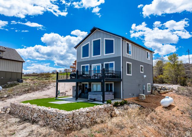 Rear view of property with a wooden deck, a patio, board and batten siding, and a jacuzzi | Image 4