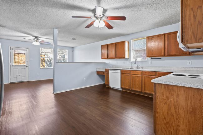 Kitchen with ceiling fan, dark wood-type flooring, white dishwasher, a textured ceiling, and sink | Image 8