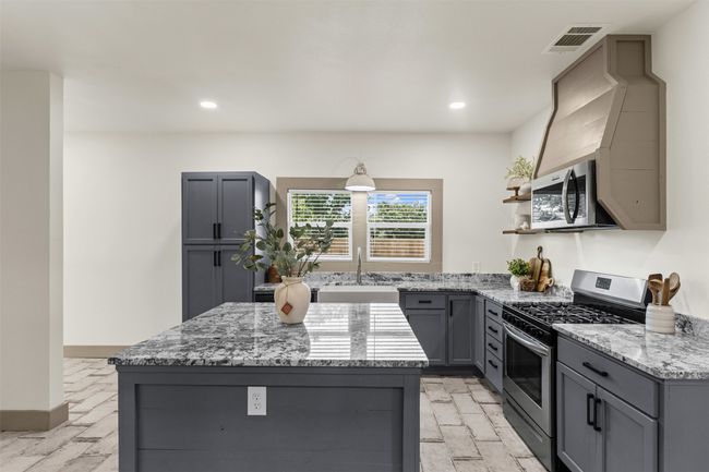 Kitchen featuring appliances with stainless steel finishes, gray cabinetry, a sink, light stone countertops, and recessed lighting | Image 18