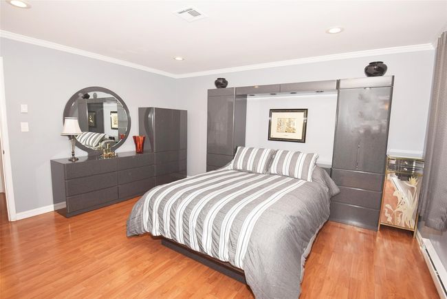 Primary Bedroom featuring a baseboard radiator, light wood-style flooring, molding | Image 14