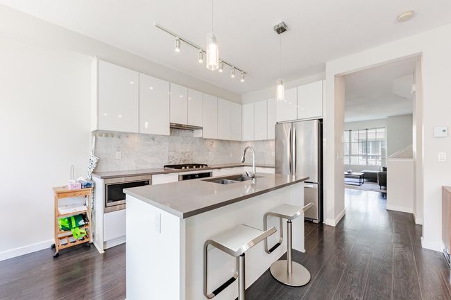 Kitchen with stainless steel appliances, modern cabinets, decorative backsplash, and decorative light fixtures | Image 13
