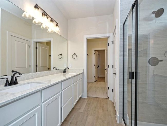 Bathroom featuring double vanity, a shower stall, and wood finished floors | Image 9