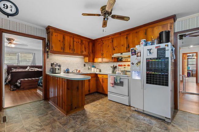 Kitchen with white appliances, a ceiling fan, healthy amount of natural light, under cabinet range hood, and wallpapered walls | Image 16