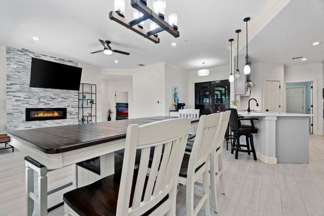 Dining room with a tiled fireplace, a ceiling fan, recessed lighting, light wood-type flooring, and a chandelier | Image 9