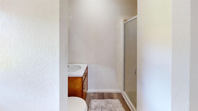 Full bathroom featuring a textured wall, vanity, a shower stall, and wood finished floors | Image 24