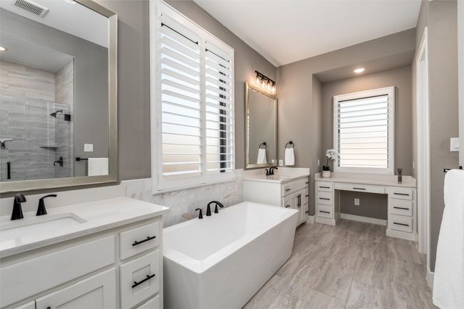 Luxury primary bath with His and Her vanities, makeup area, and freestanding tub | Image 21