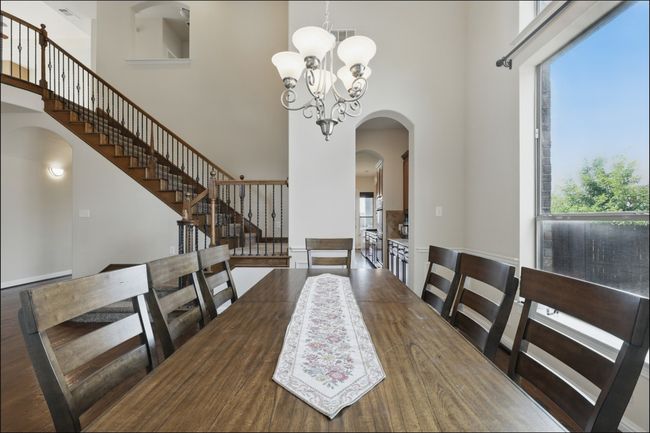 Dining room with a chandelier, arched walkways, a decorative wall, dark wood-style floors, and wainscoting | Image 8