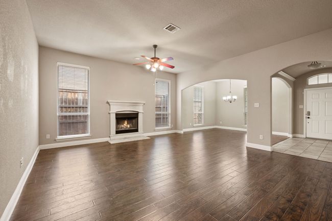 Unfurnished living room featuring a warm lit fireplace, visible vents, hardwood / wood-style flooring, and a healthy amount of sunlight | Image 9