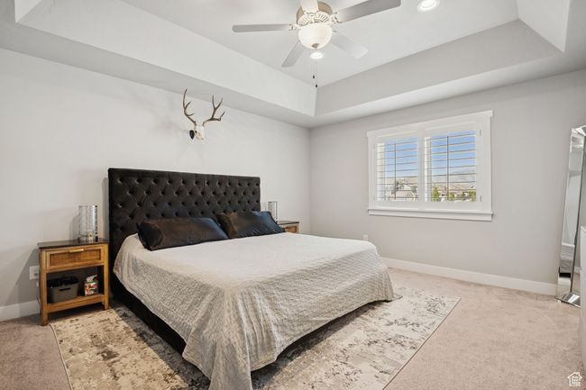 Bedroom featuring a raised ceiling, light colored carpet, and ceiling fan | Image 17