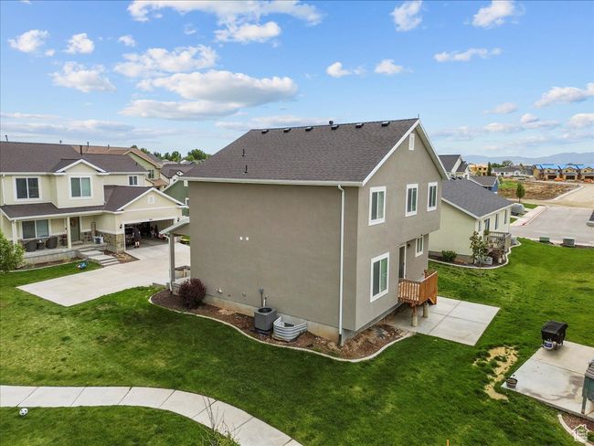 Back of property featuring stucco siding, a residential view, a lawn, a shingled roof, and a patio | Image 7