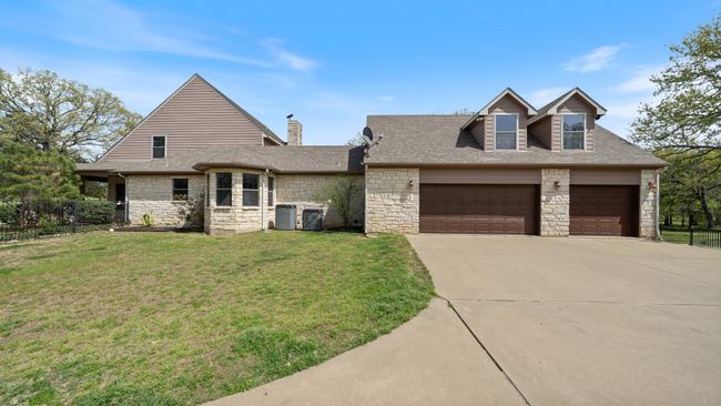 View of front of house with stone siding, driveway, a front lawn, a garage, and a shingled roof | Image 39
