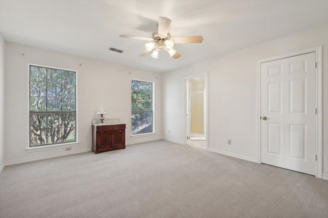 Upstairs bedroom with multiple windows, light carpet, ensuite bathroom, and a ceiling fan | Image 25