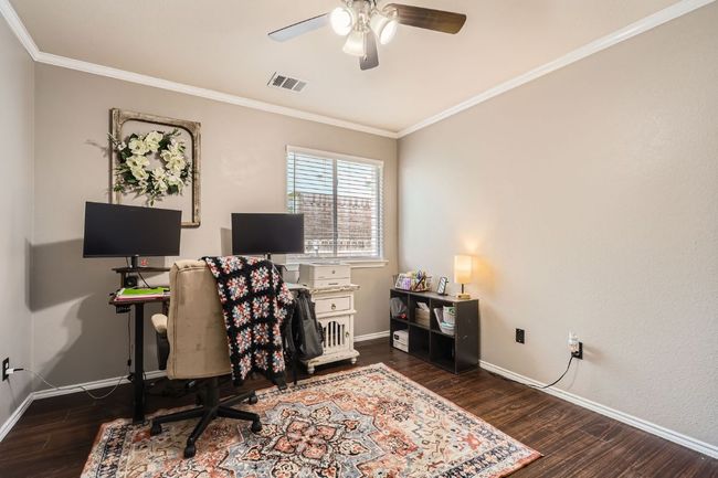 Office space with crown molding, wood finished floors, and a ceiling fan | Image 16