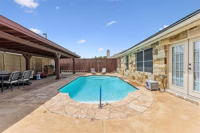View of swimming pool featuring a patio area, french doors, a fenced in pool, and a fenced backyard | Image 19