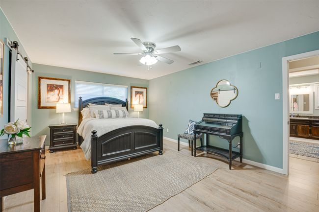 Bedroom with a barn door, light wood-style floors, and ceiling fan | Image 18