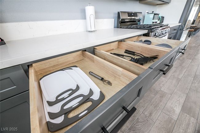 Kitchen view of light wood-style floors, stainless steel gas stove, and light countertops | Image 15