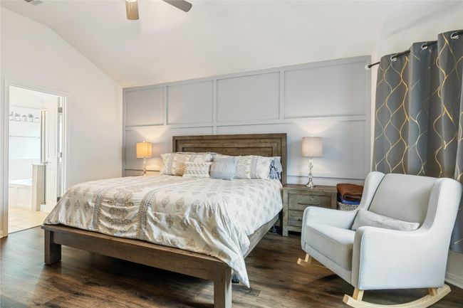 Bedroom with vaulted ceiling, a decorative wall, dark wood-type flooring, visible vents, and a ceiling fan | Image 15