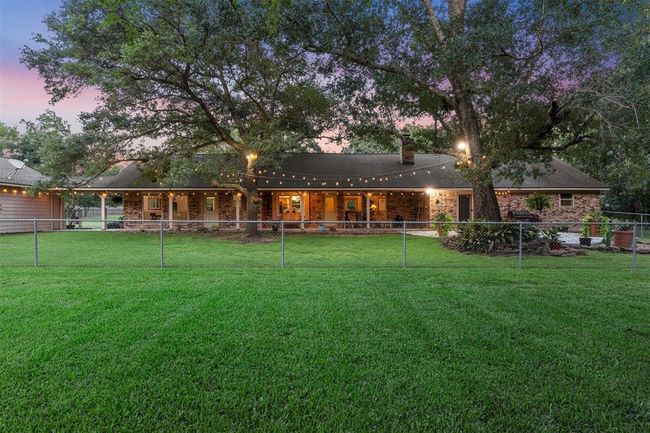 Charming brick home with a spacious four-car garage, surrounded by lush greenery. The well-maintained driveway and garden add curb appeal, while the serene backdrop of trees offers privacy and tranquility. Perfect for those seeking a peaceful setting. | Image 26