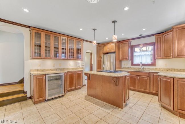Well-appointed eat-in kitchen features a central island, granite countertops, custom natural cherry cabinetry, beverage fridge and stainless steel appliances | Image 11