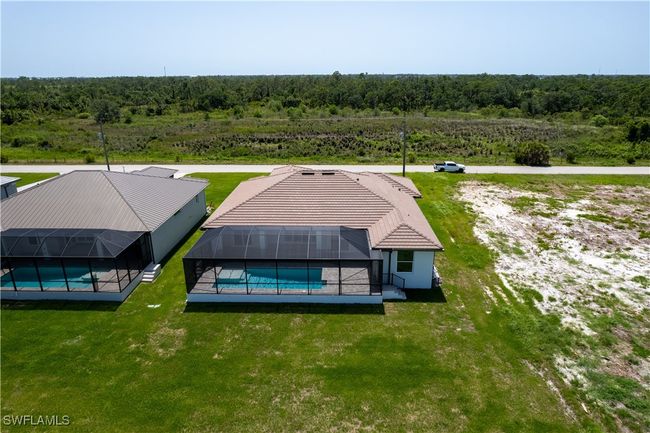 Aerial view of property and surrounding area featuring a forest and a pool area | Image 33