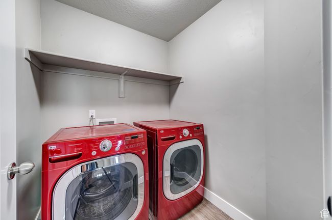 Washroom featuring a textured ceiling, separate washer and dryer, wood finished floors, laundry area, and baseboards | Image 17