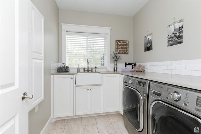 Laundry area featuring separate washer and dryer, cabinet space, marble finish floor, and a sink | Image 36