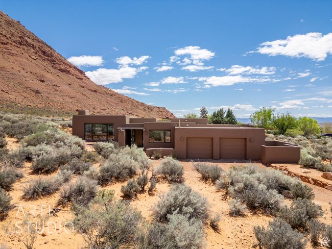 Adobe home featuring a garage, a mountain view, stucco siding, and dirt driveway | Image 58