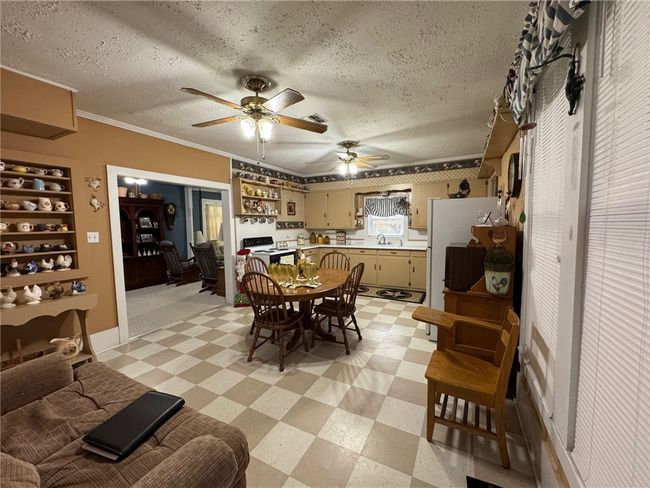 Dining space with light floors, a textured ceiling, ceiling fan, and ornamental molding | Image 13