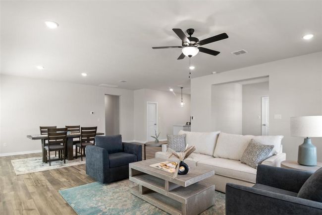 Living room with a ceiling fan, wood finished floors, baseboards, visible vents, and recessed lighting | Image 8
