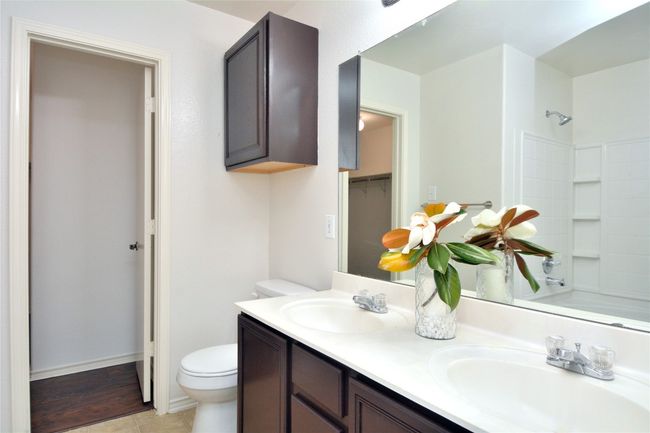 Bathroom featuring toilet, double vanity, shower / washtub combination, a closet, and tile patterned floors | Image 12