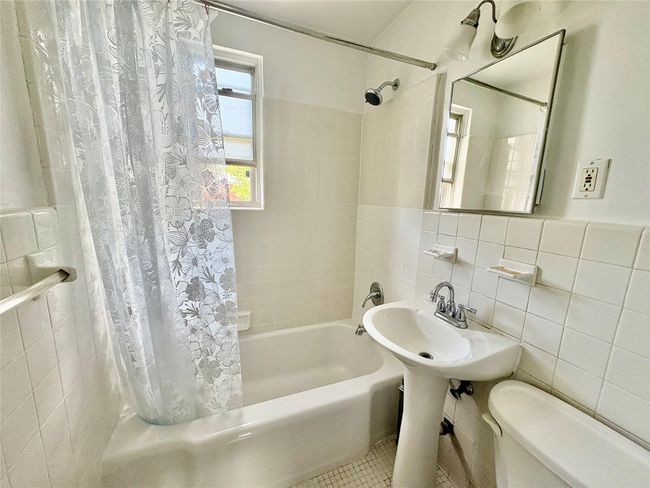 Bathroom with tile walls and shower / bathtub combination with curtain | Image 8