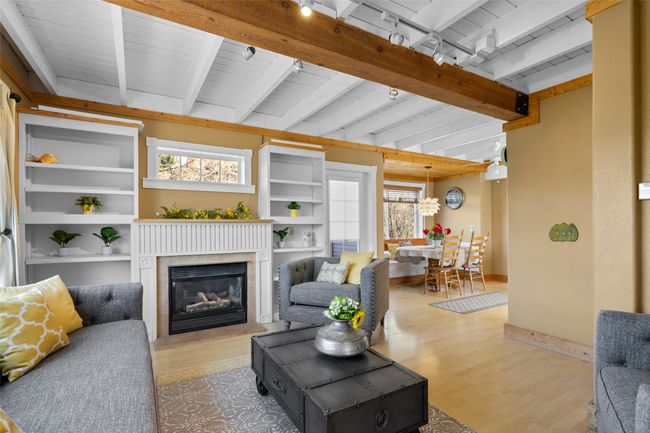 Living area featuring a glass covered fireplace, beam ceiling, and light wood finished floors | Image 11