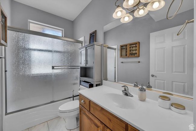 Bathroom featuring marble finish floor, enclosed tub / shower combo, an inviting chandelier, toilet, and vanity | Image 19