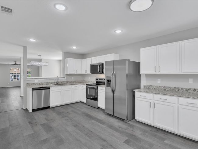 Kitchen with stainless steel appliances, a sink, white cabinetry, wood finished floors, and recessed lighting | Image 8
