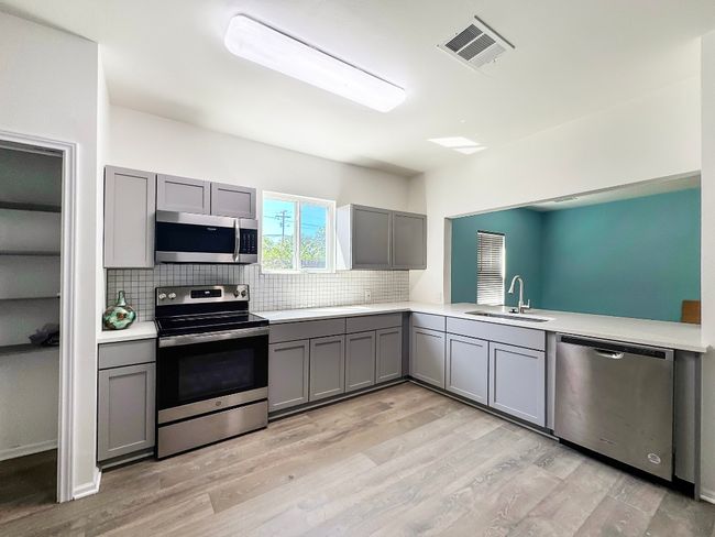 Kitchen with stainless steel appliances, gray cabinetry, a sink, and light countertops | Image 6