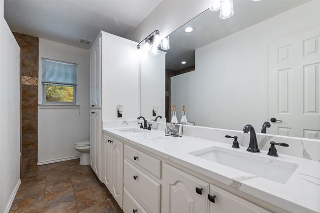 Bathroom with double vanity, baseboards, a sink, and toilet | Image 21