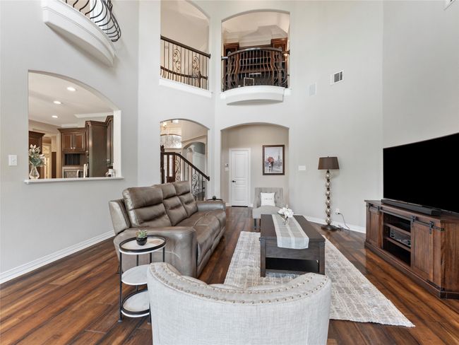 Living area with arched walkways, dark wood-style floors, stairway, a towering ceiling, and recessed lighting | Image 15
